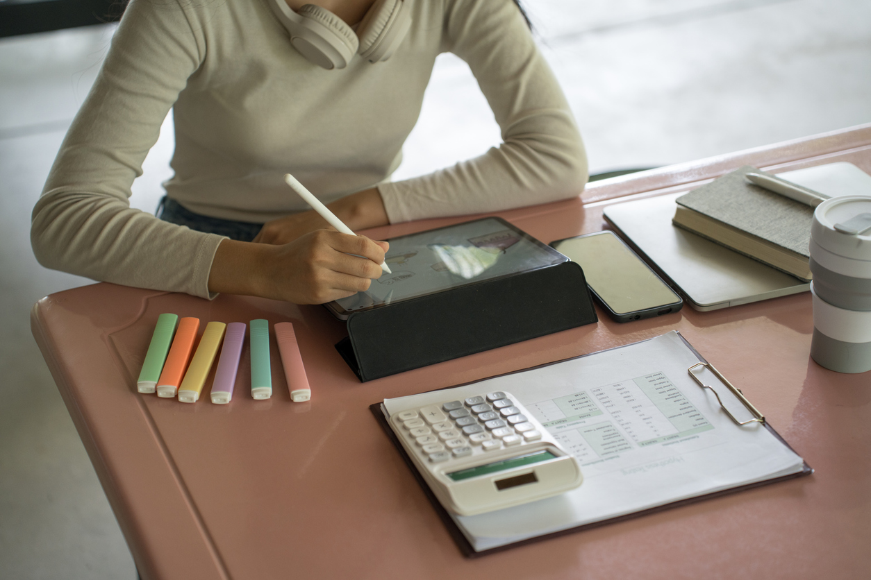 An accountant at a desk working with a calculator and tablet computer.